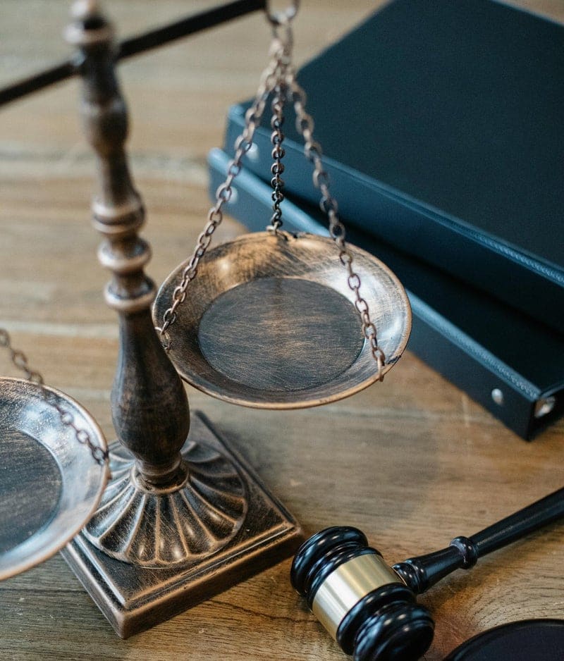 Balanza de la justicia, mazo y carpetas sobre una mesa de madera