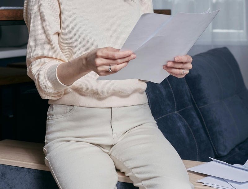 Persona leyendo una carta en casa, con sobres abiertos al lado